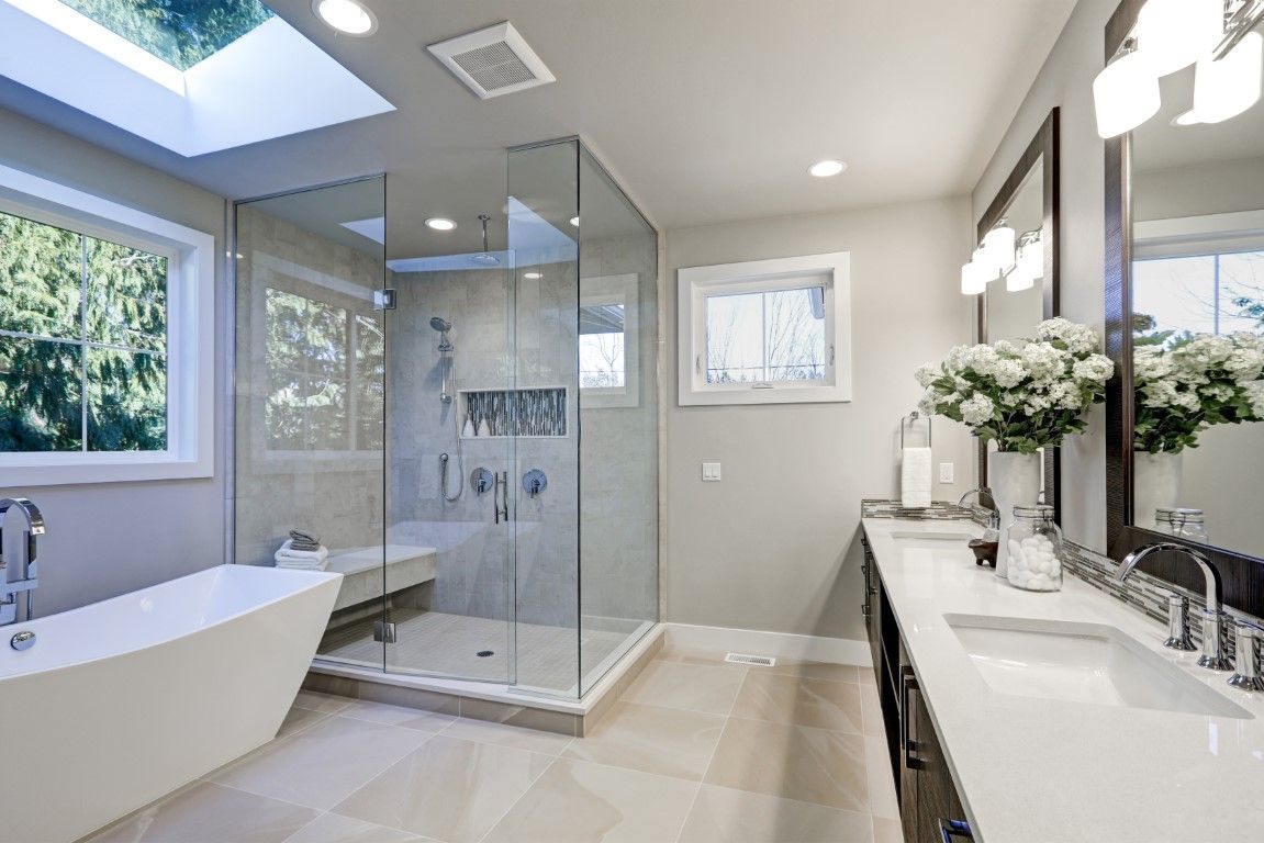 Remodeled bathroom with a glass shower enclosure, freestanding tub, and double vanity