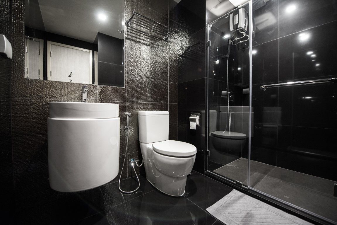 Walk-in shower with dark large-format tile, frameless glass door, and a wall-hung sink