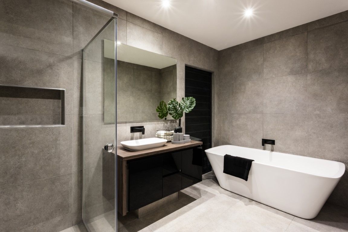 Fully renovated bathroom with large-format grey tile, a floating vanity, and a freestanding tub